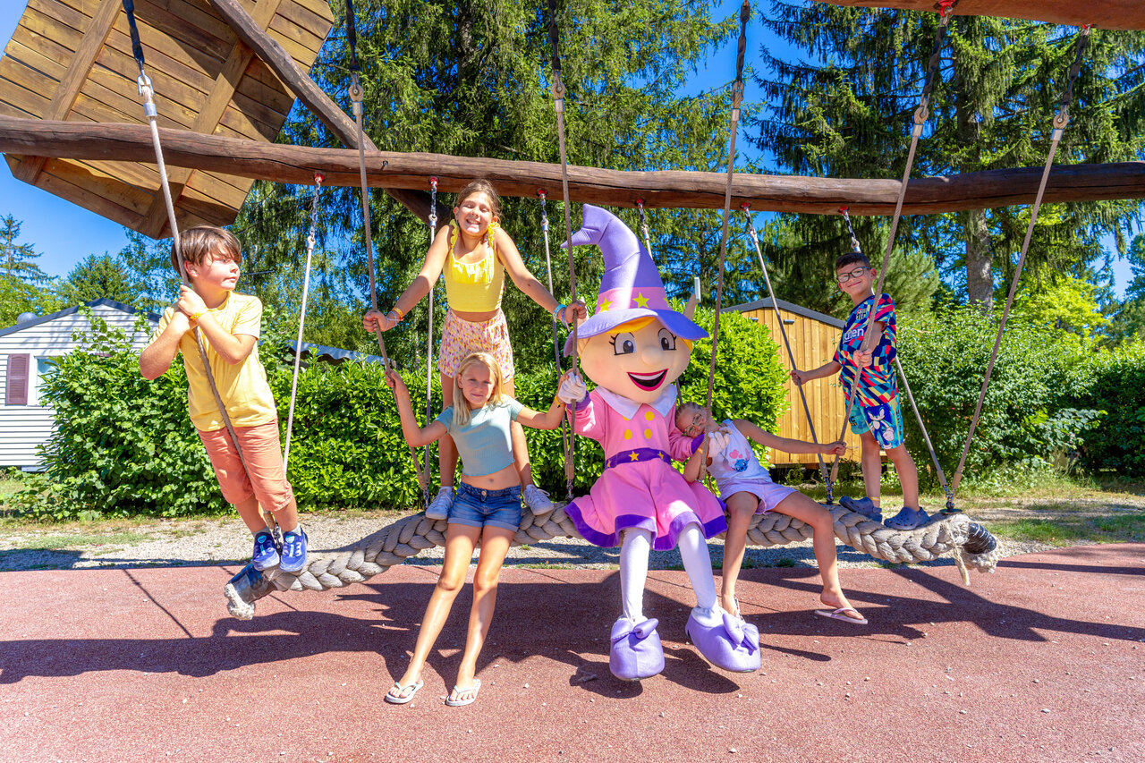 Enfants et mascotte sur balan�oire g�ante aire de jeux au camping CAPFUN R�gni�re � Villette d'Anthon.
