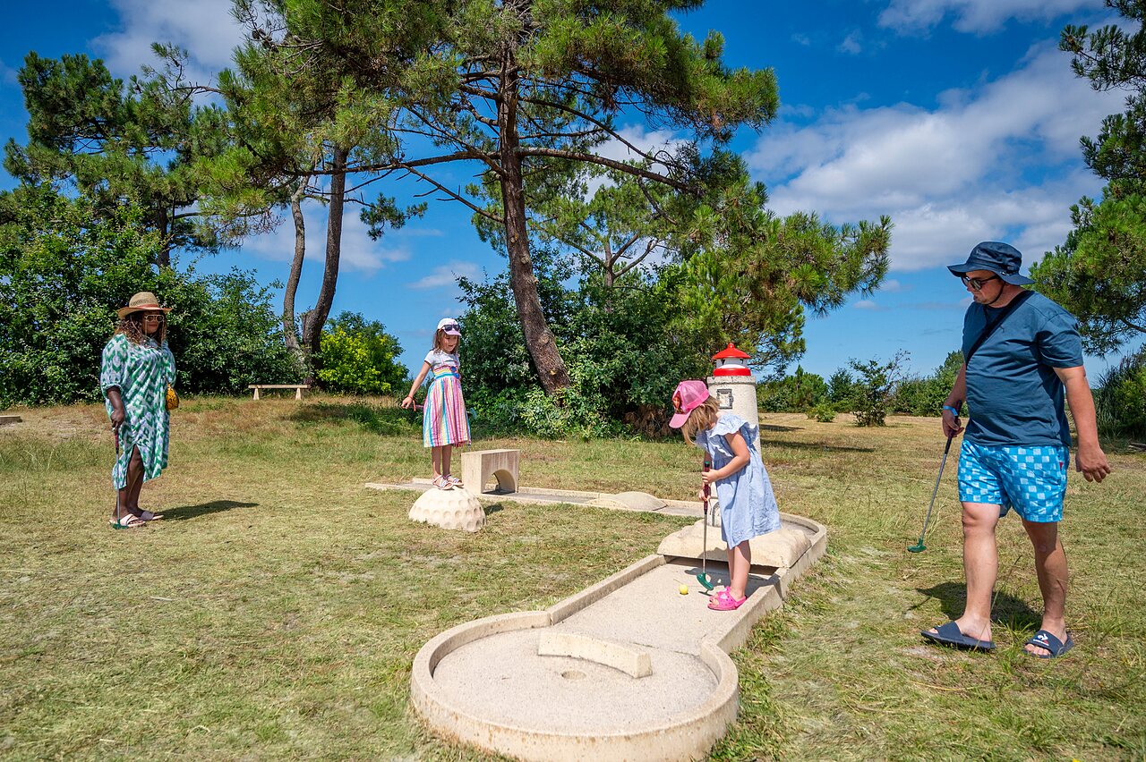 Famille jouant au mini-golf avec parcours � th�me au camping CAPFUN Roumingue � LANTON (33).
