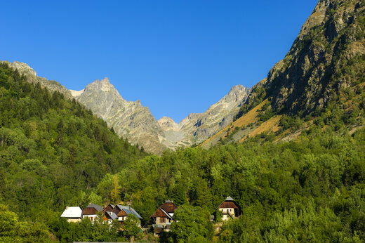 Montagnes verdoyantes et maisons traditionnelles dans une vallée alpine au camping CAPFUN Saint Colomban.
