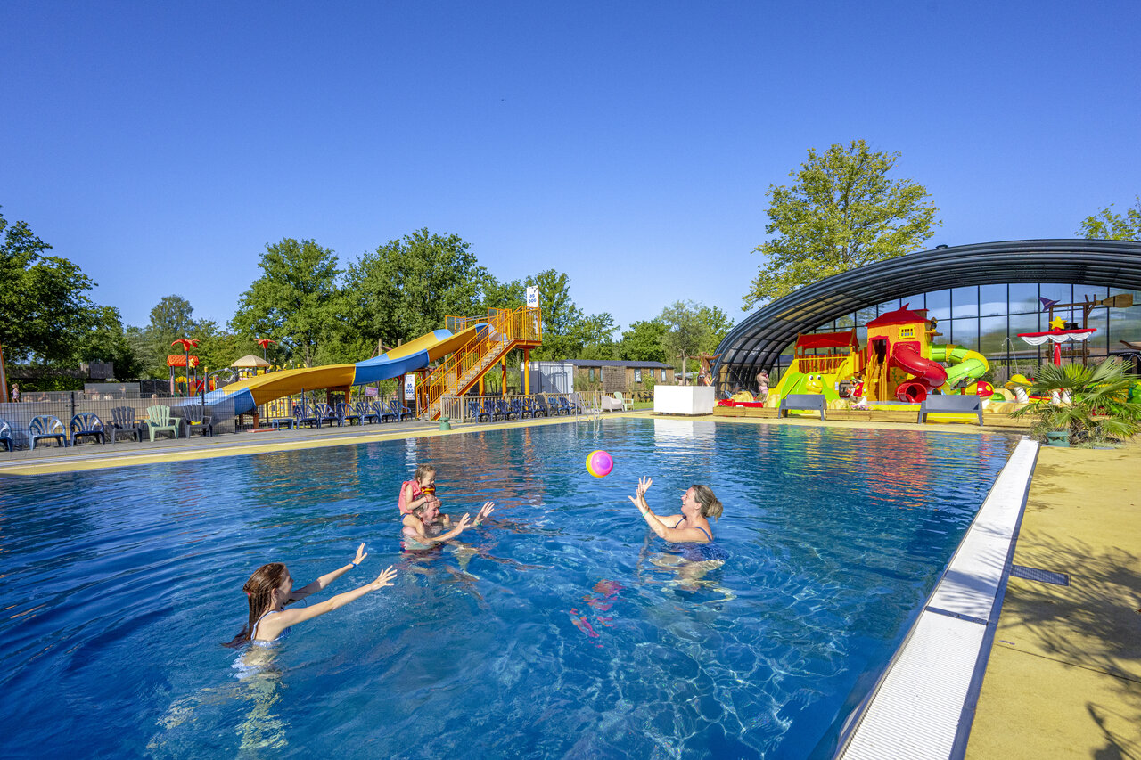 Famille jouant dans la piscine avec toboggans au camping CAPFUN De Sprookjescamping � Rheeze.