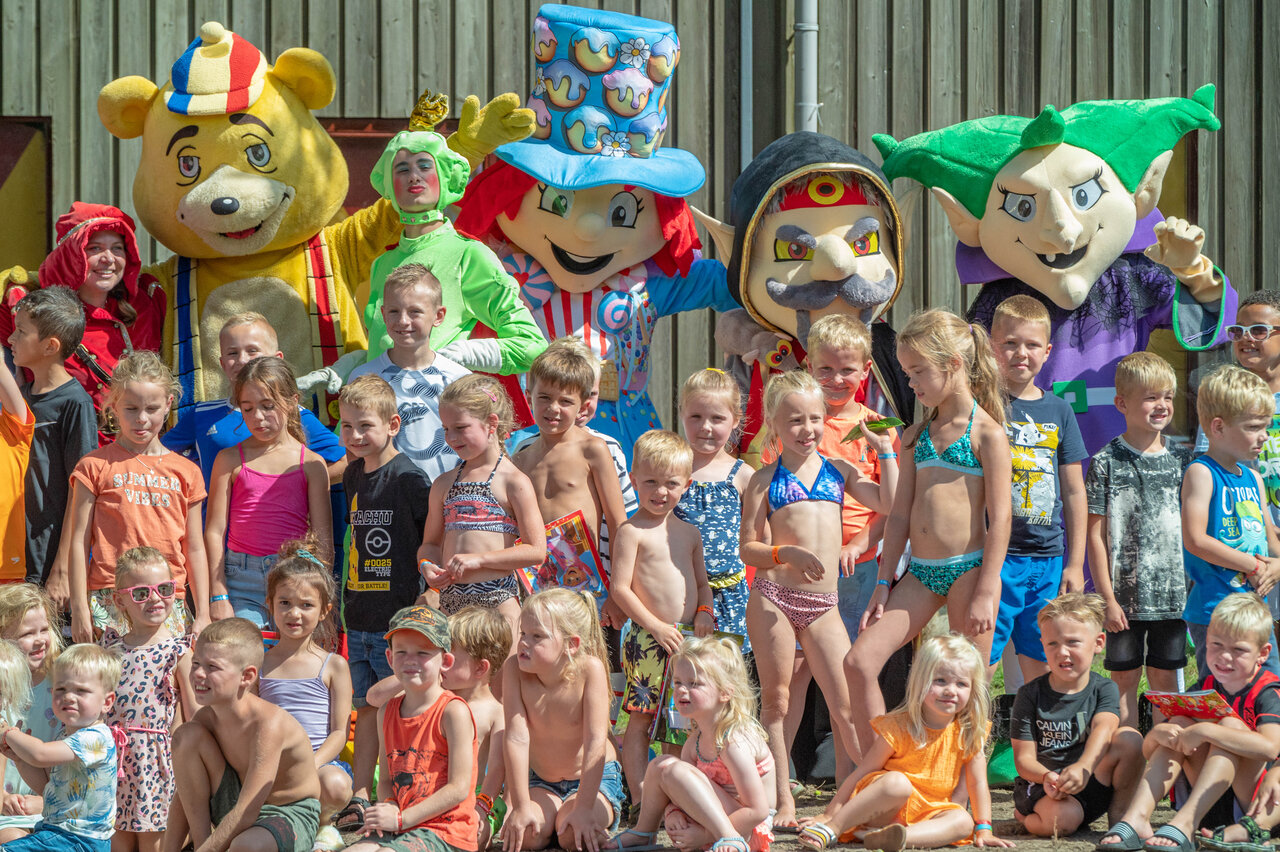 Enfants souriants avec mascottes de l'�quipe d'animation au camping CAPFUN De Sprookjescamping � Rheeze.