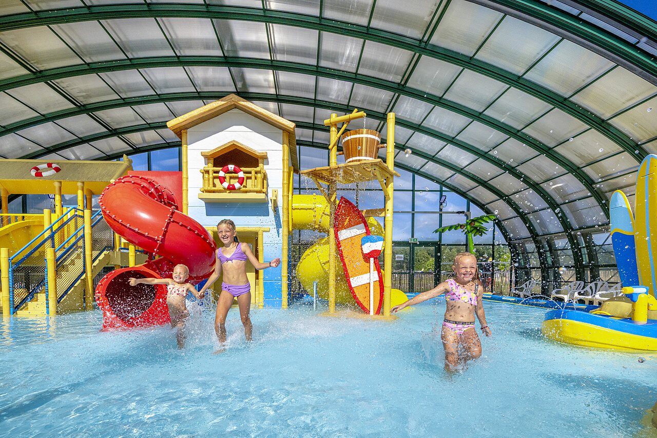 Enfants jouant dans l'espace aquatique couvert avec toboggans au camping CAPFUN Vakantiepark Capfun het Stoetenslagh � Rheezerveen.