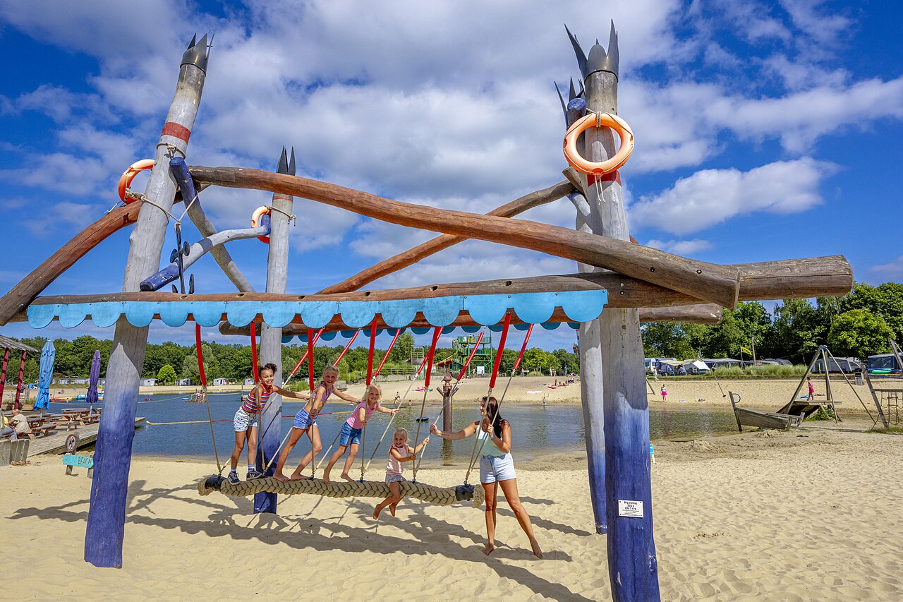 Structure de jeux en bois sur la plage de sable avec enfants au camping CAPFUN Vakantiepark Capfun het Stoetenslagh � Rheezerveen.