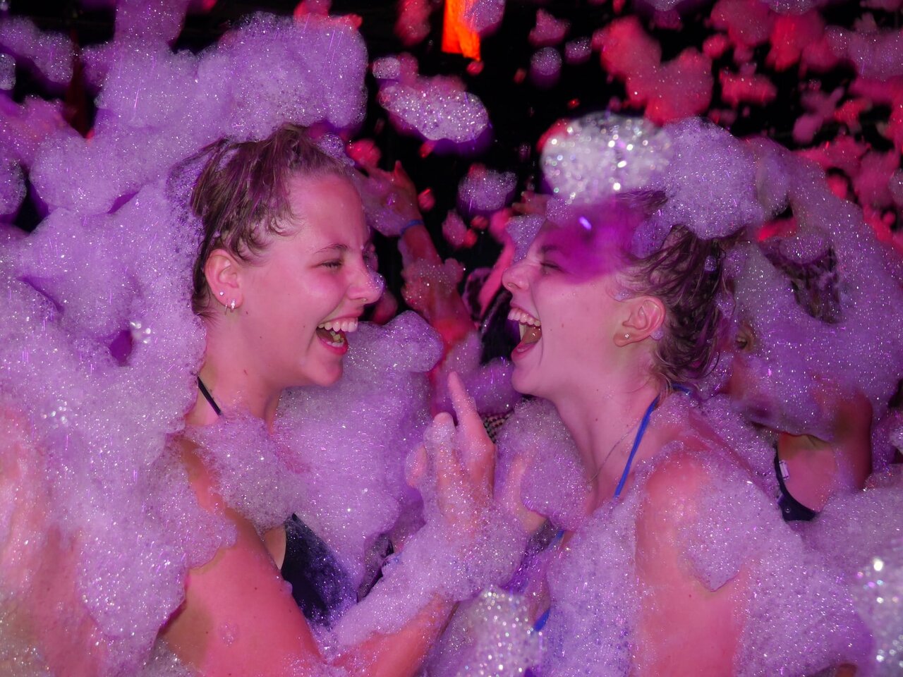 Deux jeunes femmes riant dans la mousse lors d'une animation au camping CAPFUN Suzel � Sainte-Croix-en-Plaine (68).