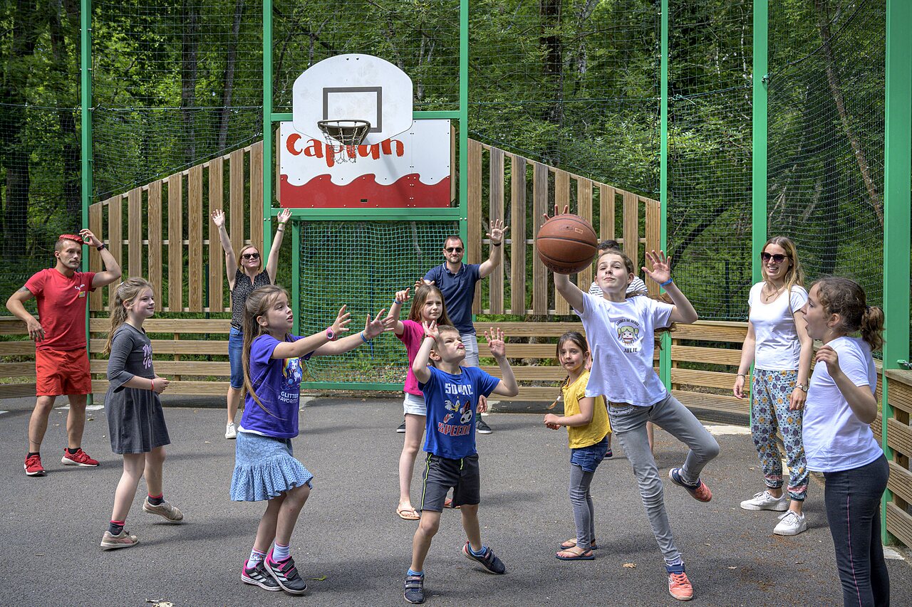Terrain de basketball avec enfants et adultes jouant au camping CAPFUN Talaris Vacances � Lacanau (33).