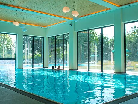 Piscine intérieure lumineuse avec baies vitrées au camping CAPFUN Tecklenburg à Tecklenburg-Leeden (49).