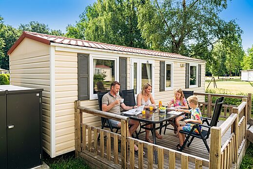 Famille déjeunant sur la terrasse d'un Mobil-home au camping CAPFUN Tecklenburg.