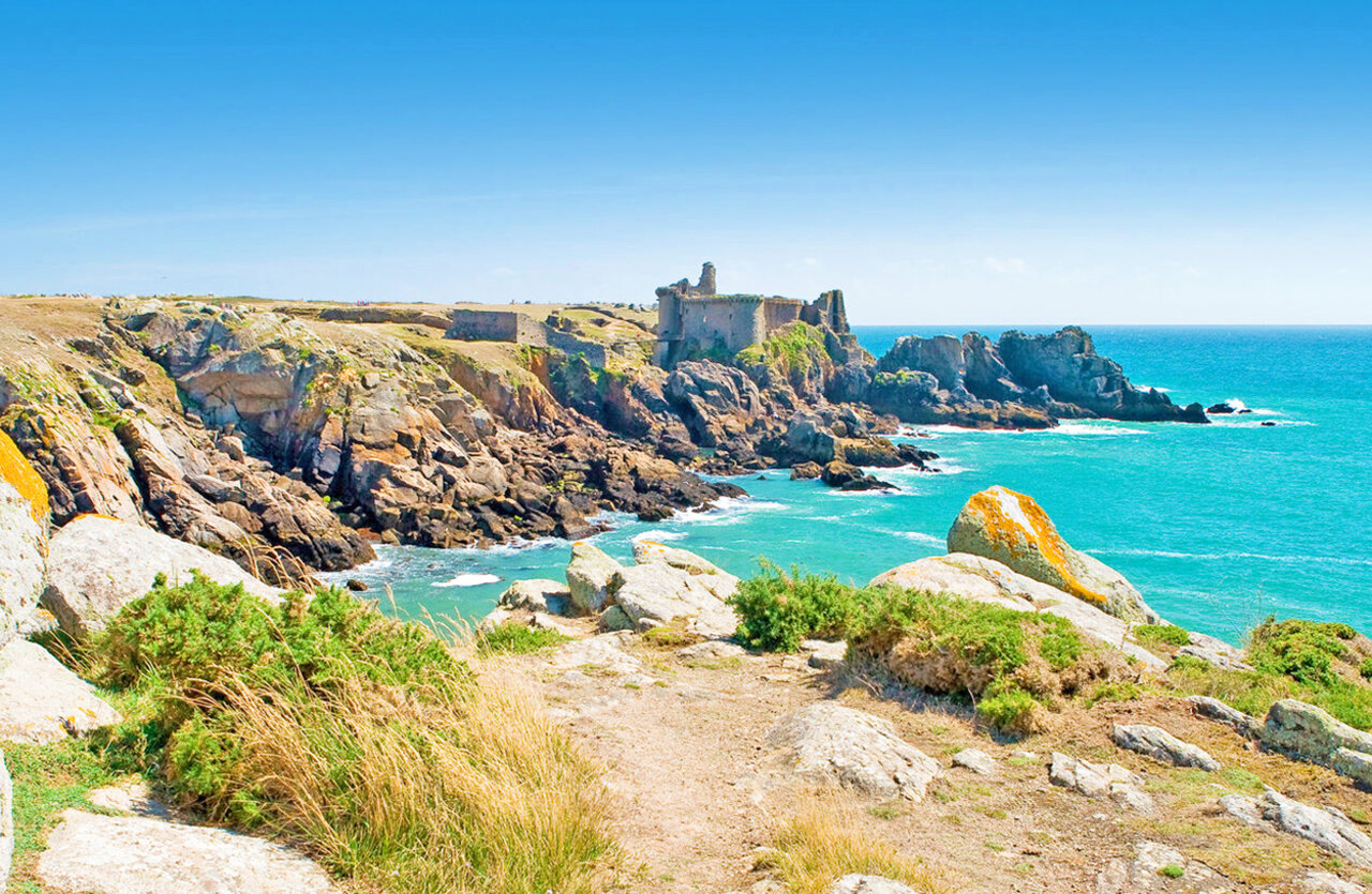 Falaises rocheuses, mer turquoise et ruines historiques au camping CLICOCHIC Plage des Tonnelles.