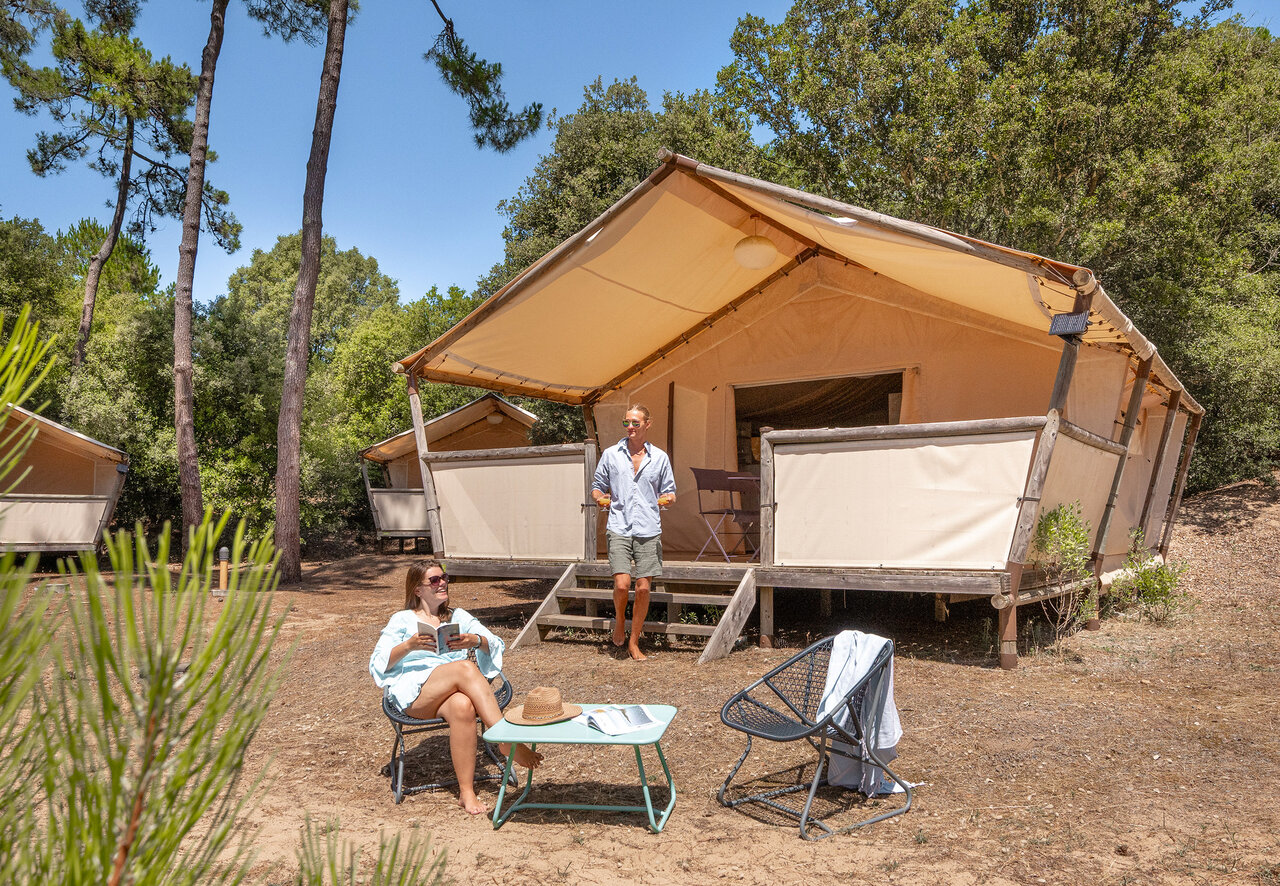 Couple relaxant devant tente lodge glamping au camping CLICOCHIC Plage des Tonnelles (85).