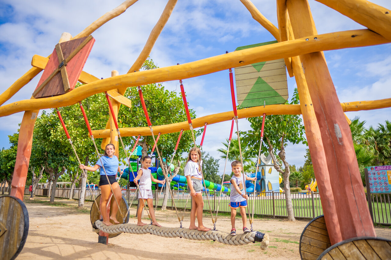 Enfants s'amusant sur un pont de corde dans l'aire de jeux au camping CAPFUN Tordera-Nacions � Malgrat de Mar.