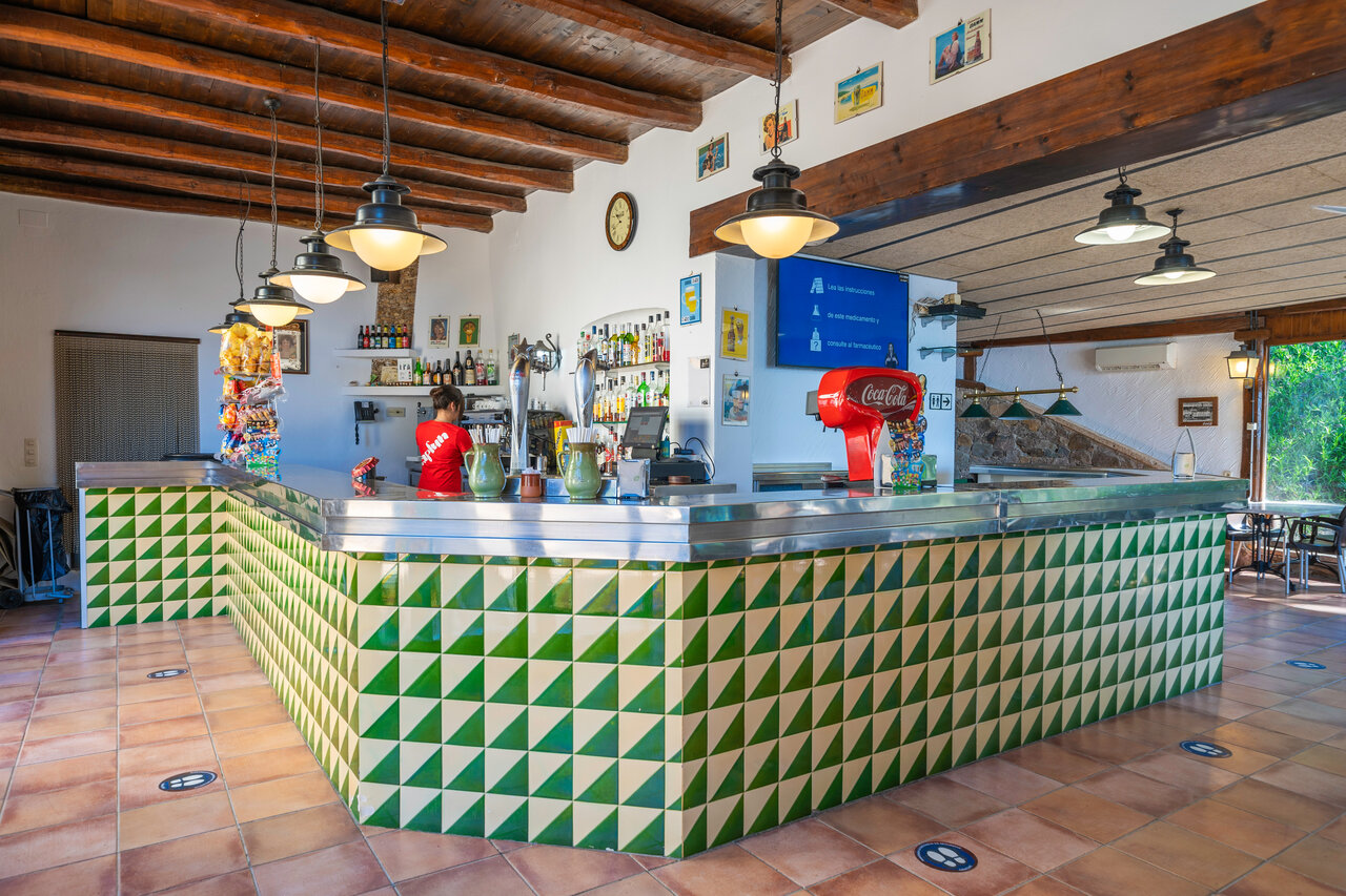 Bar int�rieur avec comptoir carrel� et serveuse au camping CAPFUN Treumal � Platja d'Aro.