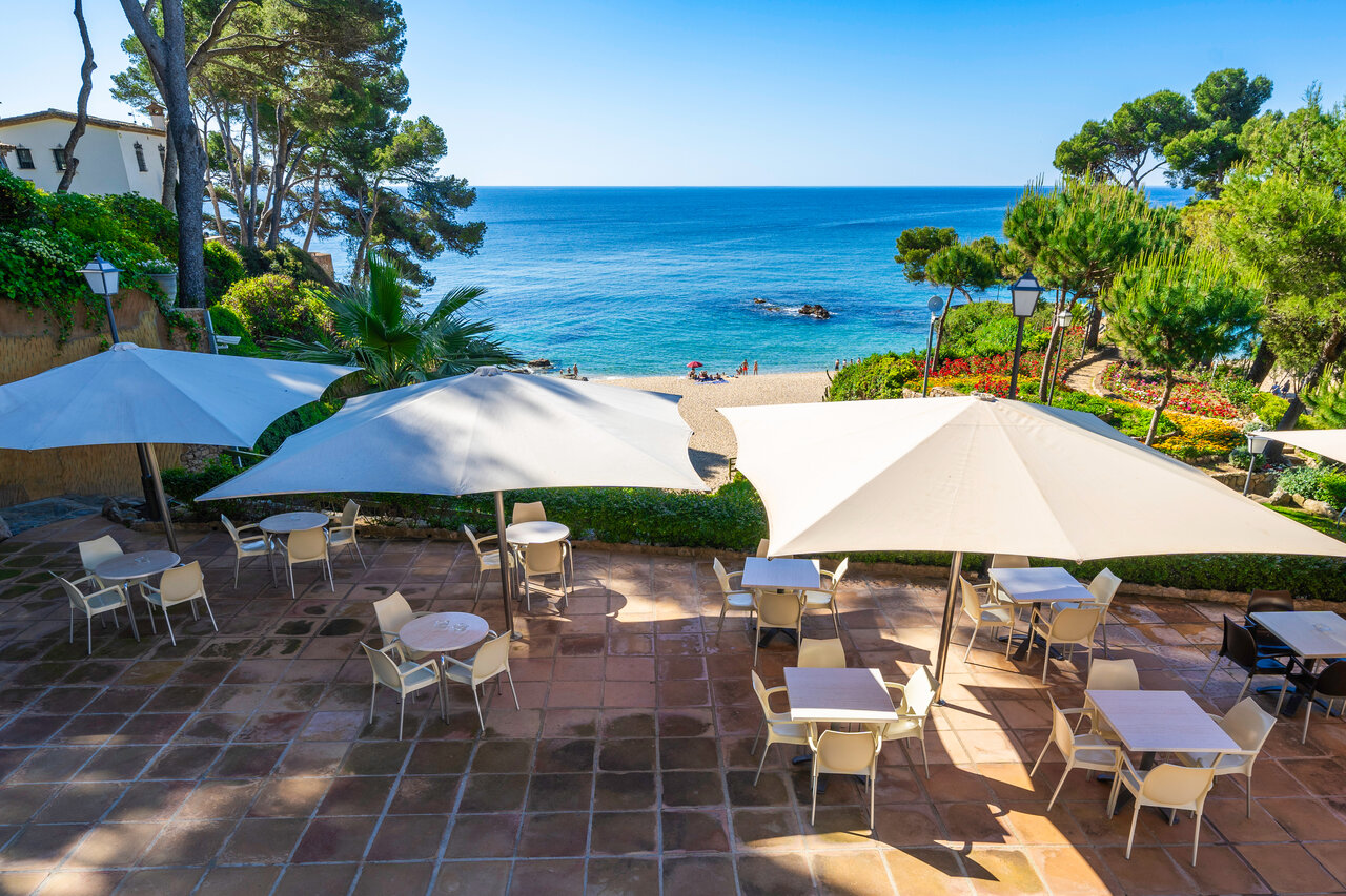Terrasse de restaurant avec parasols, plage et mer M�diterran�e au camping CAPFUN Treumal � Platja d'Aro (17).