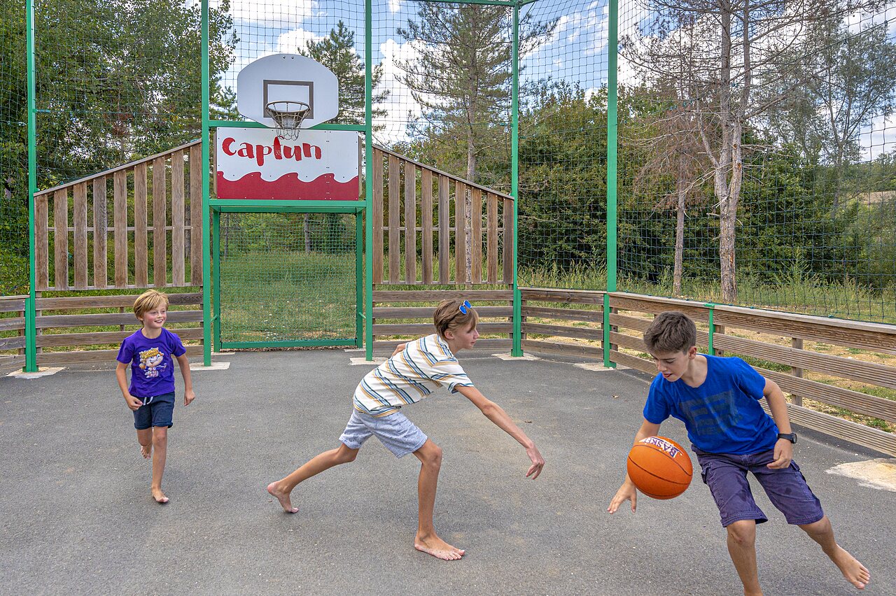 Terrain multisport avec enfants jouant au basketball au camping CAPFUN Ullule � Tournon d'Agenais (47).