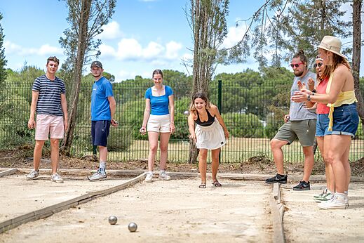 Jeunes jouant à la pétanque sur un terrain dédié au camping CAPFUN Vignes d'Or à Serignan.