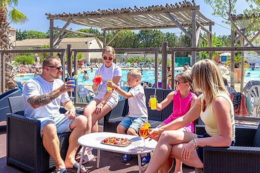 Famille au bar de la piscine avec boissons, camping CAPFUN Vignes d'Or.
