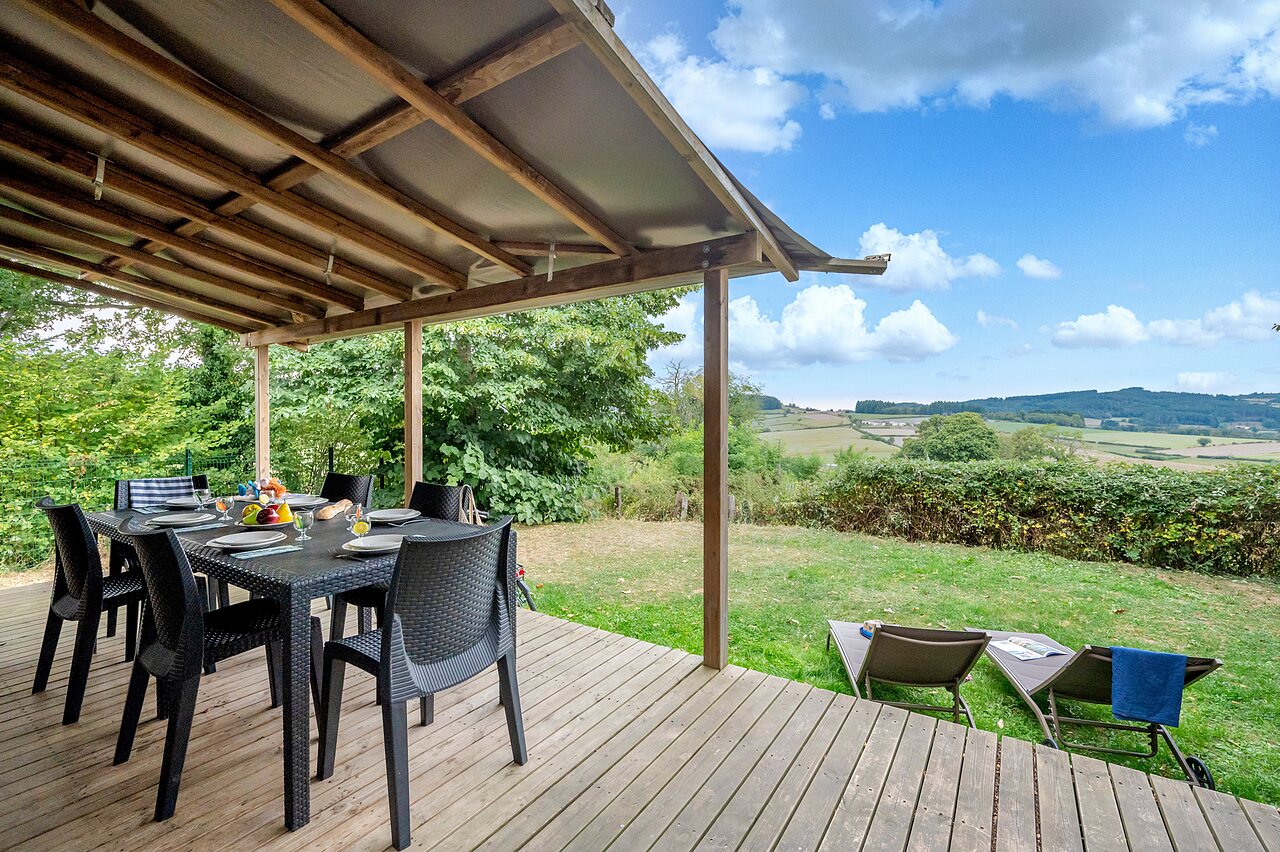 Terrasse couverte, table � manger, vue nature au camping CLICOCHIC Village des Meuniers � Dompierre-les-Ormes (71).