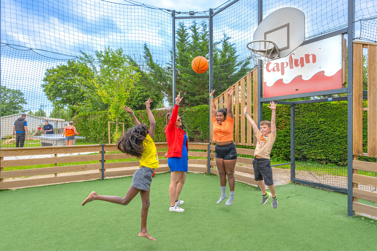 Enfants et adultes jouant au basketball sur terrain multisport au camping CAPFUN Le Village Parisien � VARREDDES (77).