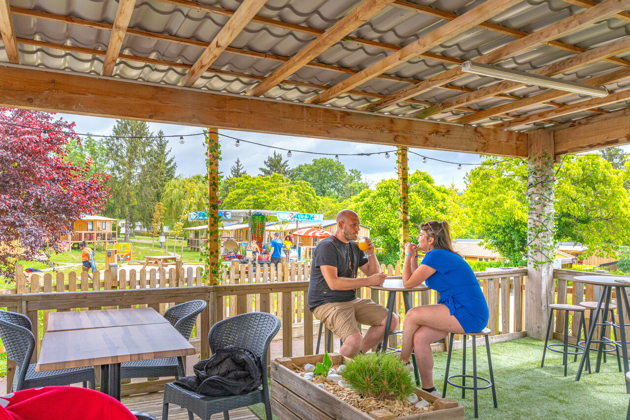 Terrasse de bar anim�e, couple et aire de jeux au camping CAPFUN Le Village Parisien � VARREDDES (77).