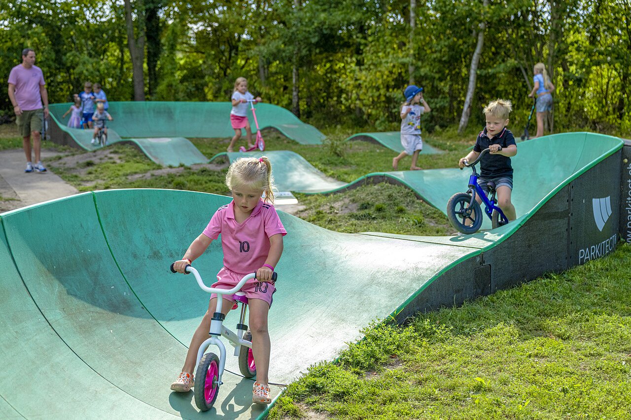 Enfants jouant sur le pump track � v�lo et trottinette au camping CAPFUN Vlinderloo � Enschede.