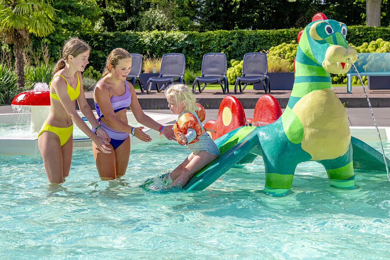 Enfants jouant dans la pataugeoire avec toboggan dinosaure au camping CAPFUN het Winkel � Winterswijk.