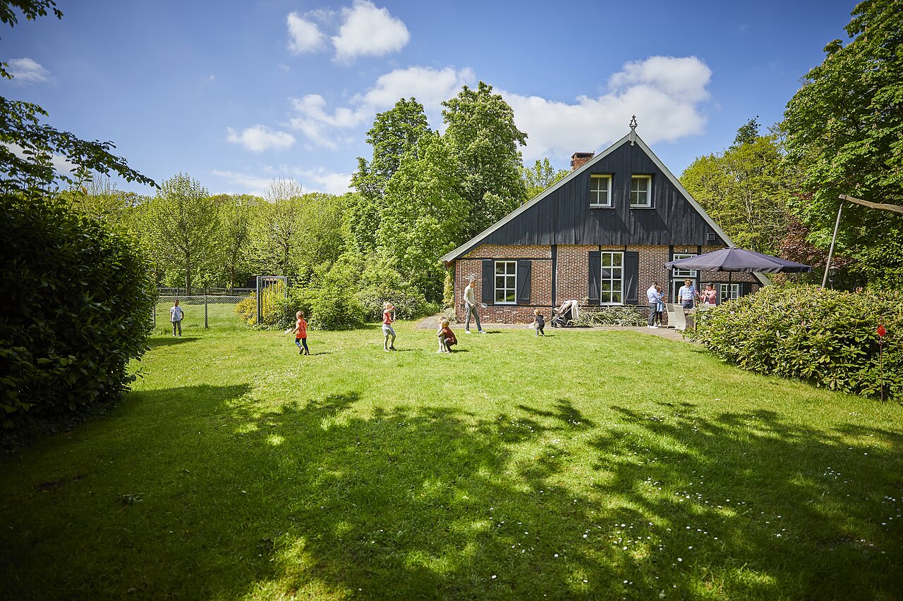 Enfants jouant sur la pelouse devant un b�timent traditionnel au camping CAPFUN het Winkel � Winterswijk.