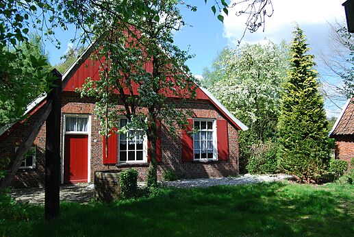 Maison traditionnelle en briques, volets rouges, jardin fleuri au camping CAPFUN het Winkel à Winterswijk.
