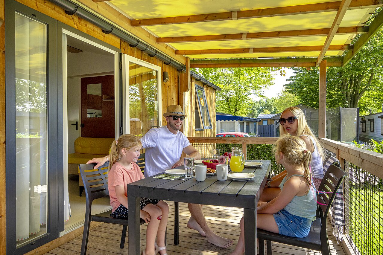 Famille d�jeunant sur la terrasse d'un mobile-home au camping CAPFUN de Wondermolen � Molenschot.